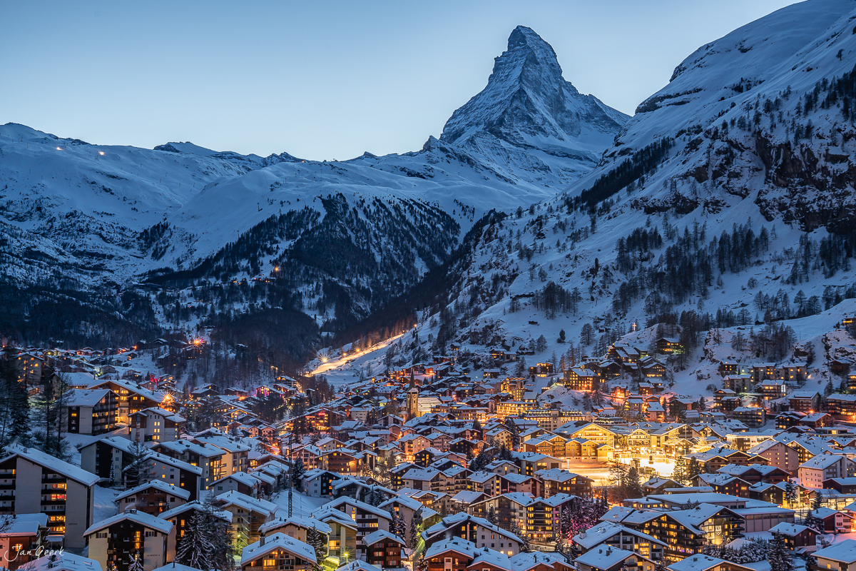 Winterliches Dorf Zermatt mit schneebedeckten Häusern und beleuchteten Fenstern bei Dämmerung, Wallis Schweiz – Jan Geerk Fotograf Basel