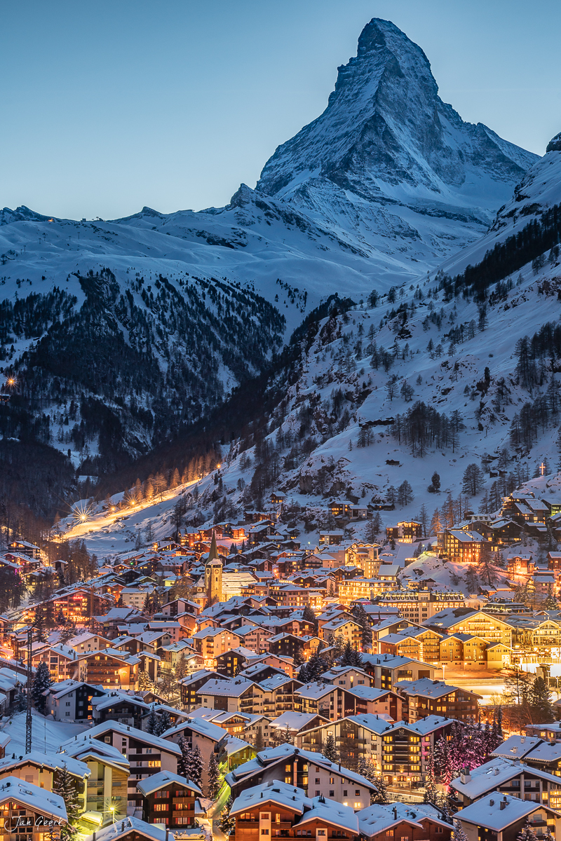 Verschneites Alpendorf Zermatt mit beleuchteten Häusern bei Dämmerung, Matterhorn im Hintergrund, Winterabend Wallis Schweiz – Jan Geerk Fotograf Basel