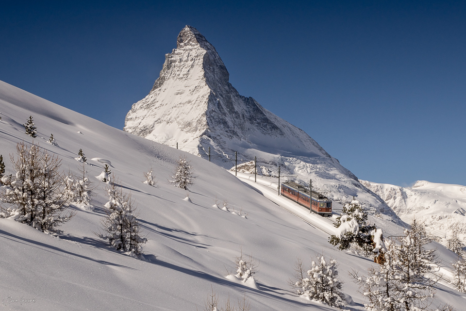 Zahnradbahn am Matterhorn bei Zermatt im Winter, schneebedeckte Berglandschaft unter blauem Himmel – Jan Geerk Fotograf Basel