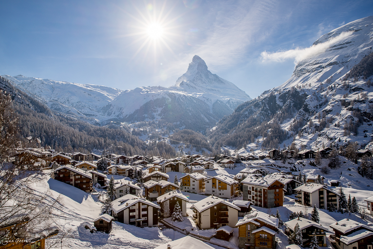 Winterliches Dorf mit schneebedeckten Chalets und Matterhorn im Hintergrund bei Sonnenschein in Zermatt Wallis Schweiz – Jan Geerk Fotograf Basel