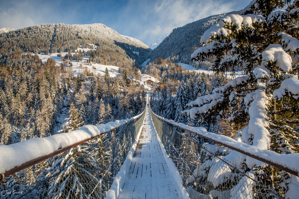 Hängebrücke über verschneite Berglandschaft in Goms während Winterstimmung Wallis Schweiz – Jan Geerk Fotograf Basel
