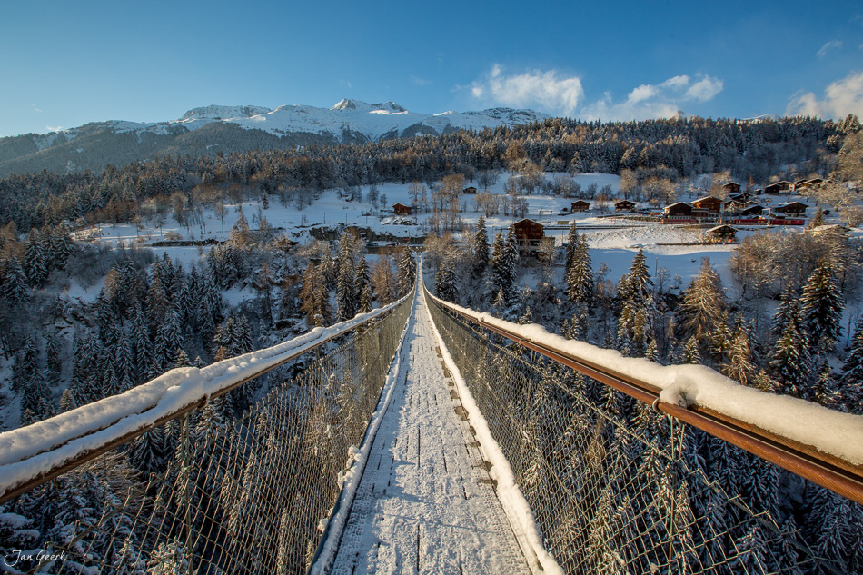 Hängebrücke über verschneite Landschaft mit Dörfern und Bergen im Goms Wallis Winter Schweiz Jan Geerk Fotograf Basel
