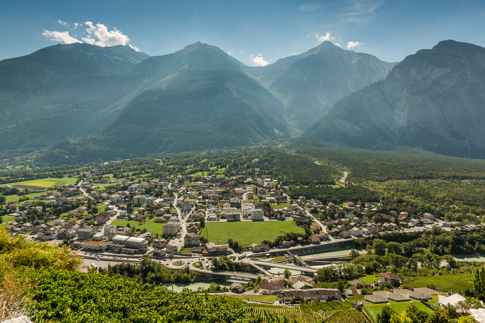 Luftaufnahme von Sitten im Wallis mit Alpenkulisse, grünem Rhonetal und Schlössern unter blauem Himmel – Schweiz, Jan Geerk Fotograf Basel