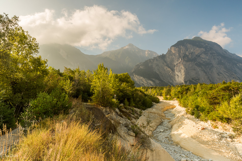 Alpiner Fluss im Illgraben bei Leuk mit dramatischen Bergen und grüner Vegetation im Sommer, Wallis Schweiz – Jan Geerk Fotograf Basel