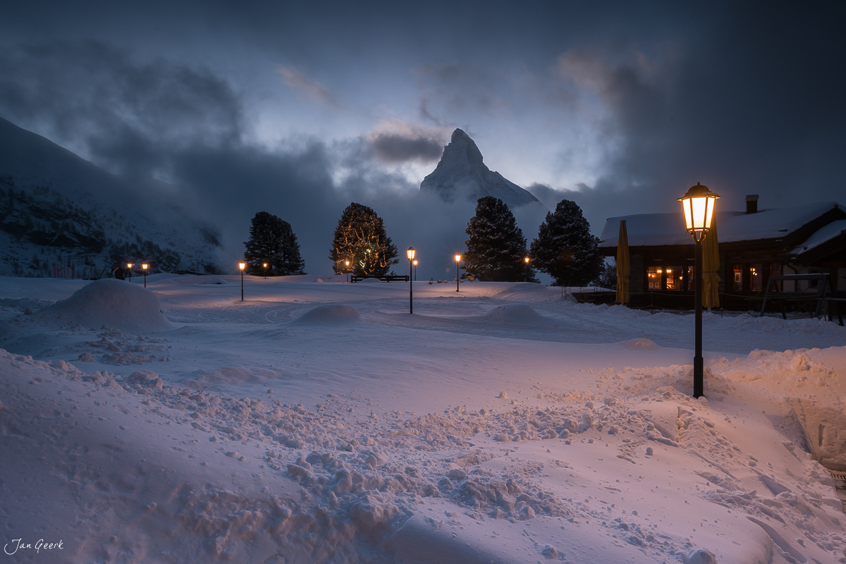 Verschneite Winterlandschaft in Zermatt mit beleuchteten Chalets, Matterhorn im Hintergrund, Schweiz – Jan Geerk Fotograf Basel