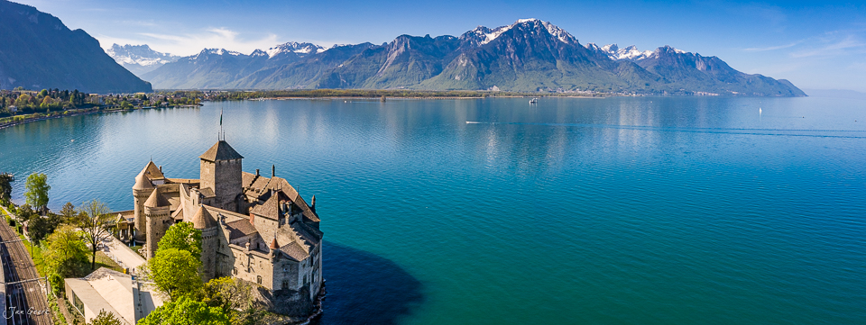 Schloss Chillon am Genfersee mit schneebedeckten Alpen im Frühlingslicht, Luftaufnahme Schweiz – Jan Geerk Fotograf Basel