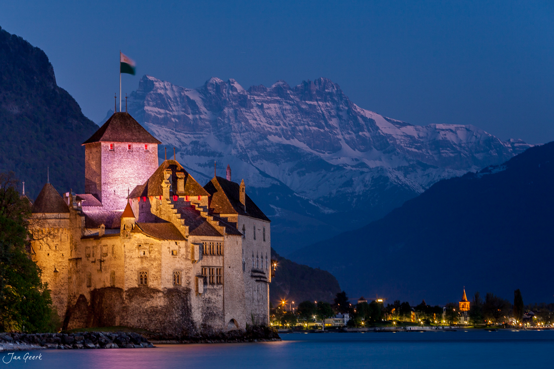 Schloss Chillon am Genfersee bei Einbruch der Dämmerung, beleuchtet vor schneebedeckten Alpen, Westschweiz Schweiz – Jan Geerk Fotograf Basel