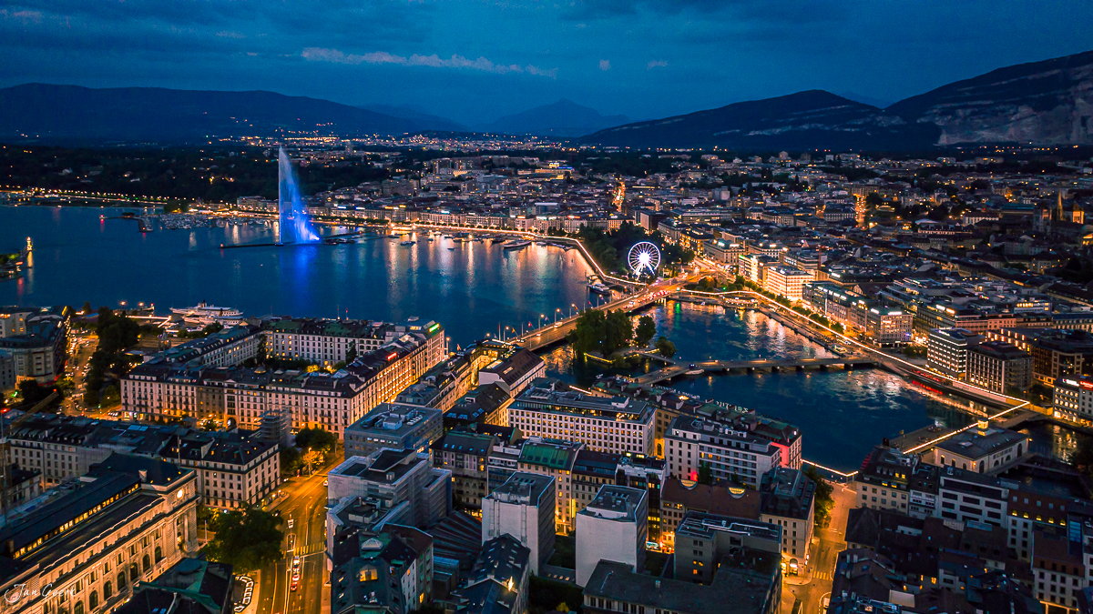 Luftaufnahme Genf bei Nacht mit leuchtenden Gebäuden und blauem See Westschweiz Schweiz Jan Geerk Fotograf Basel