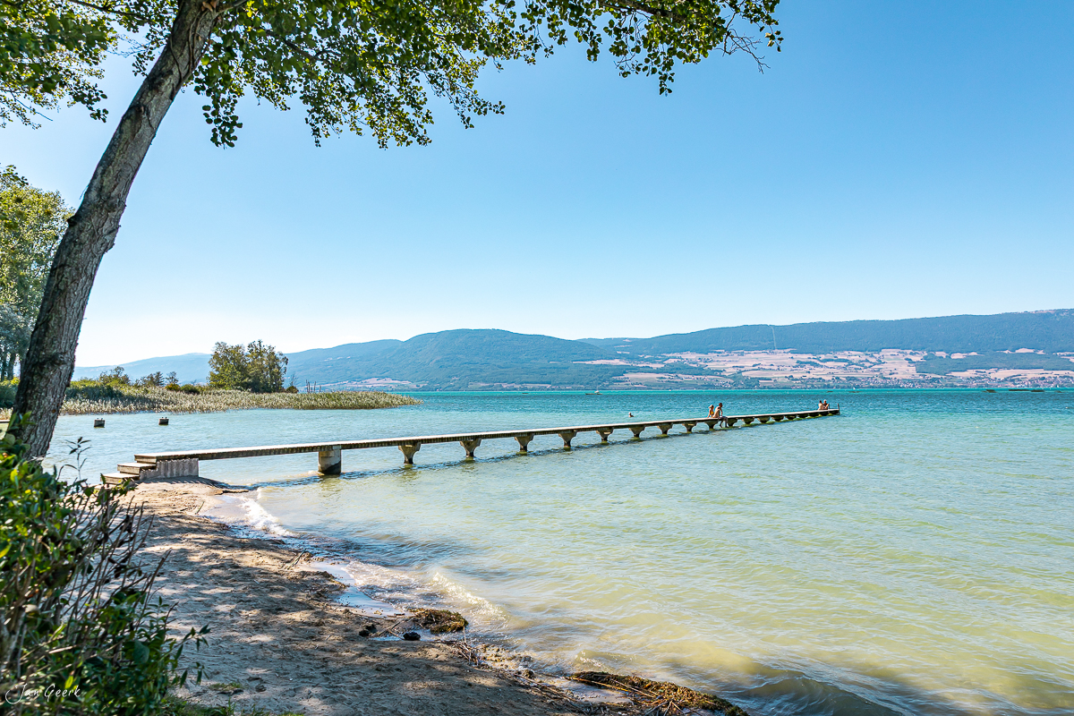 Holzsteg am Strand von Estavayer-le-Lac mit türkisblauem Wasser, Bergen und Sommersonne, Schweiz – Jan Geerk Fotograf Basel