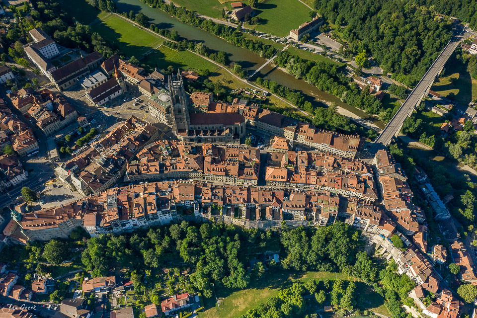 Luftaufnahme der Altstadt Freiburg mit Kathedrale Saint-Nicolas im Sommer, umgeben von grünen Wäldern und der Saane – Jan Geerk Fotograf Basel Schweiz