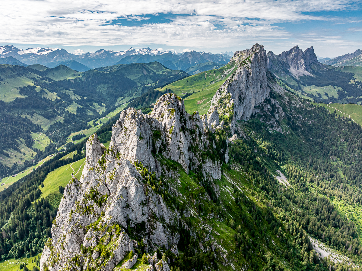 Dramatische Kalksteinpfeiler der Gastlosen bei Jaun mit grünen Alpenwiesen, Sommerliche Luftaufnahme der Voralpen Schweiz – Jan Geerk Fotograf Basel