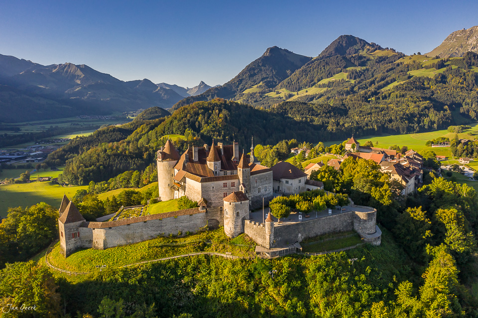 Schloss Gruyères in der Sommersonne umgeben von grünen Wiesen und Berglandschaft der Westschweiz – Jan Geerk Fotograf Basel