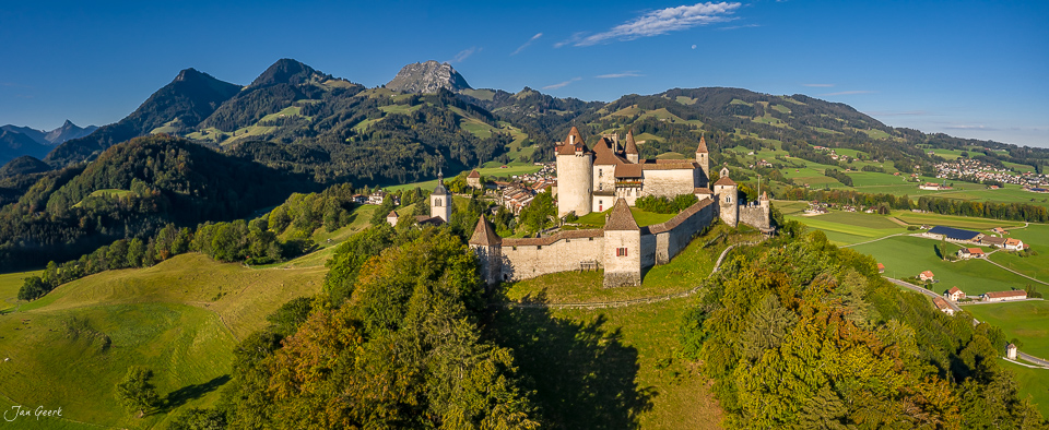 Schloss Gruyeres auf grüner Anhöhe mit Alpenpanorama Sommerlicht Westschweiz Schweiz Jan Geerk Fotograf Basel