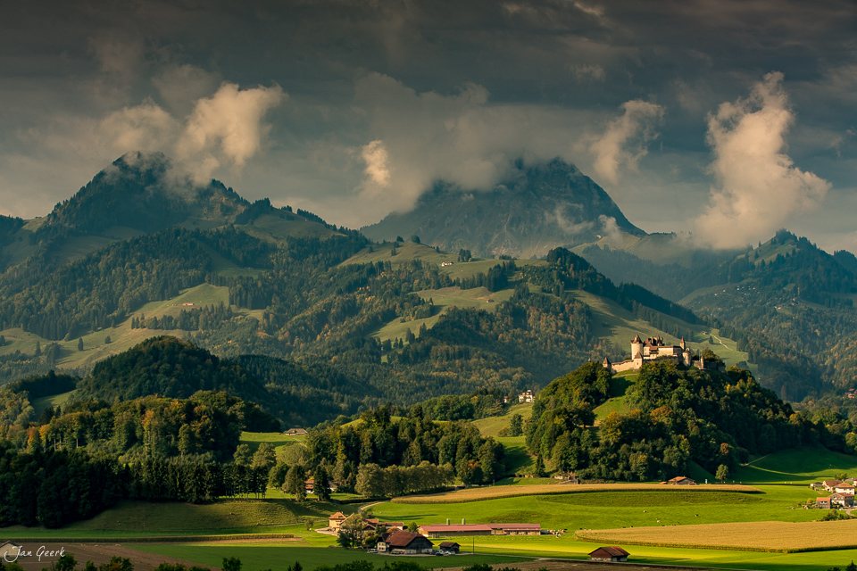 Schloss Greyerz auf grünem Hügel mit Alpenpanorama, Sommerlichtstimmung Westschweiz – Jan Geerk Fotograf Basel