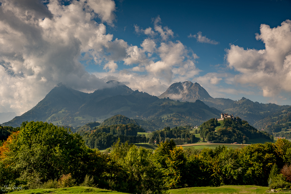 Berglandschaft Greyerz mit Schloss auf Hügel, grüne Wiesen und Wälder, Sommerlicht, Westschweiz – Jan Geerk Fotograf Basel