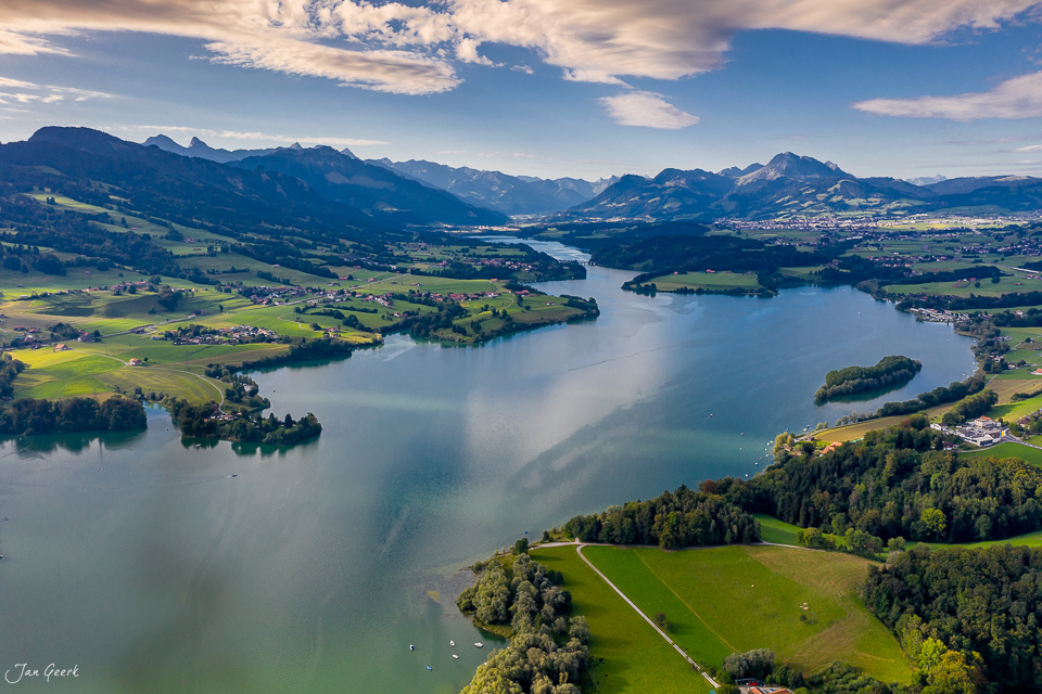 Luftaufnahme des Greyerz Sees mit grünen Uferlandschaften, Bergen und Sommerterrassen in der Westschweiz – Jan Geerk Fotograf Basel