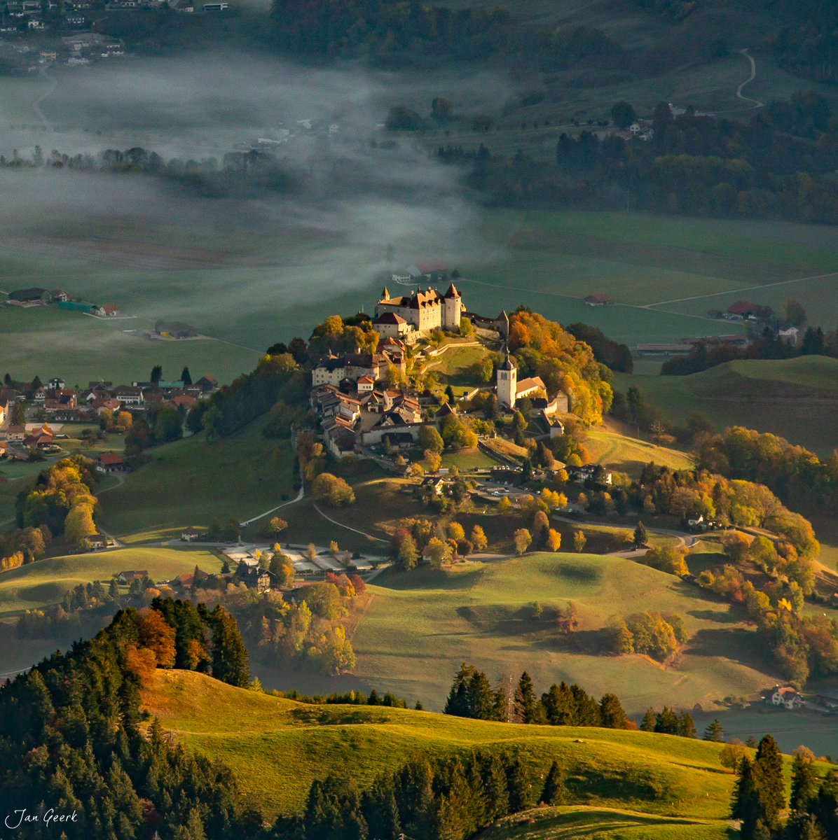 Schloss Gruyères auf Bergkuppe mit Herbstwald und Morgennebel in der Westschweiz – Jan Geerk Fotograf Basel