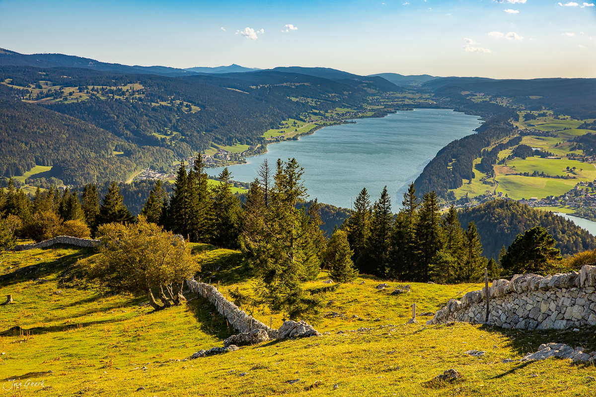 Luftaufnahme des Lac de Joux im Sommer mit grünen Weiden, Fichtenwäldern und Berglandschaft der Schweiz – Jan Geerk Fotograf Basel