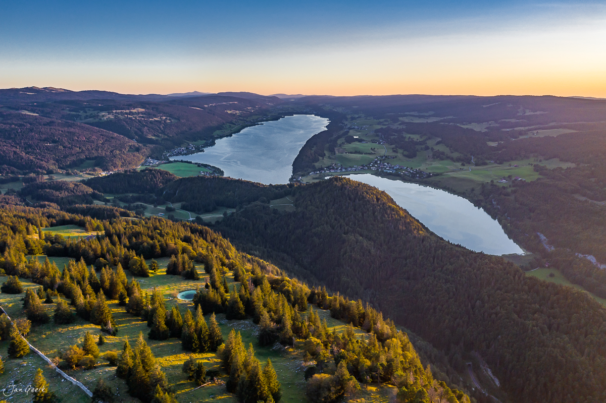 Luftaufnahme Vallée de Joux mit zwei Seen, Herbstlicht über Jurawäldern und grünen Wiesen, Westschweiz – Jan Geerk Fotograf Basel