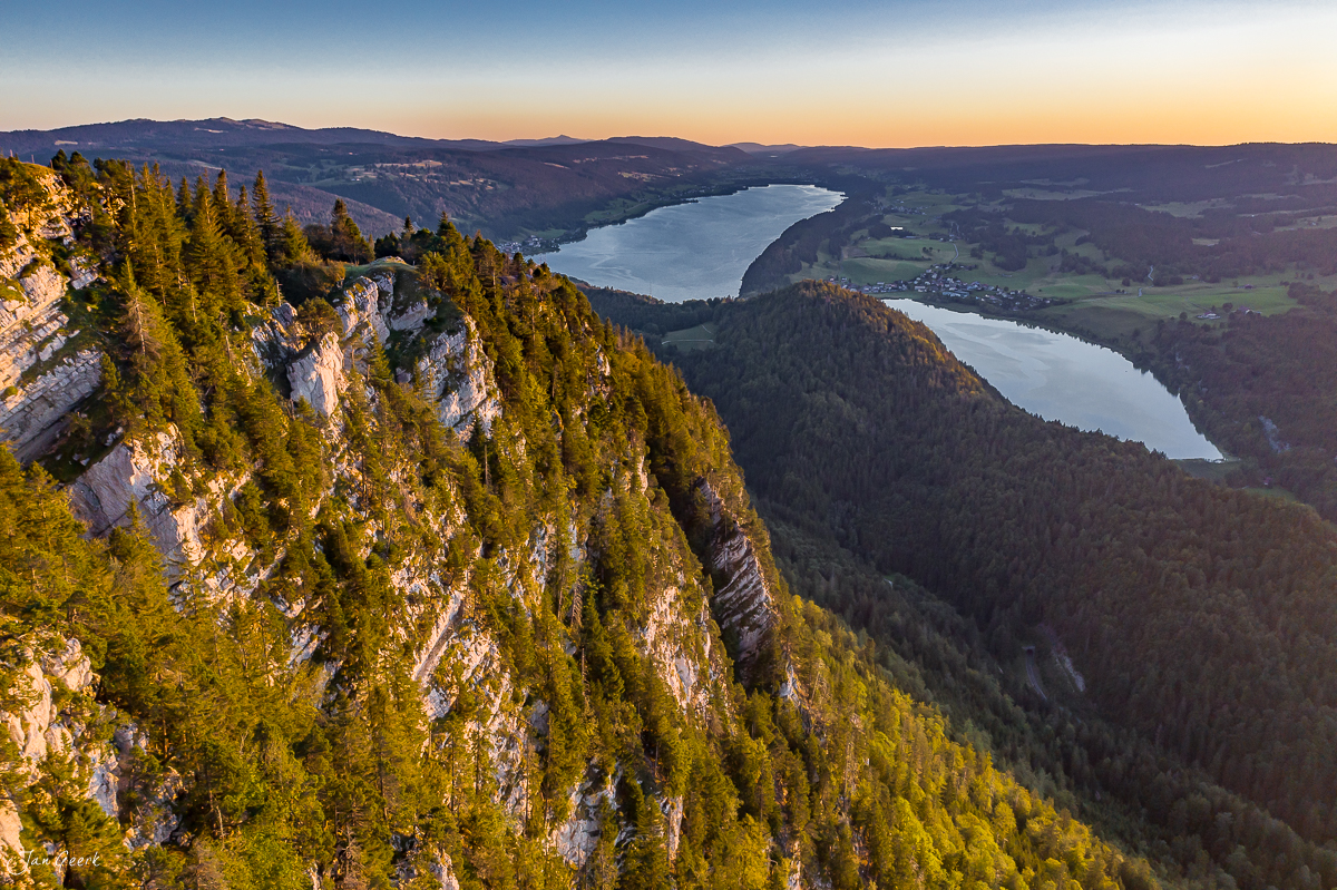 Luftaufnahme Vallée de Joux mit zwei Seen, Felsklippen und Nadelwald in Sommerlicht, Jura Schweiz – Jan Geerk Fotograf Basel