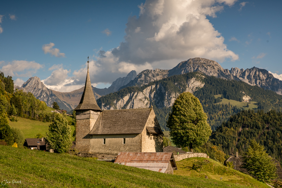 Kirche von Rossinière mit Spitzturm in grüner Berglandschaft, Pays-d'Enhaut Waadt Westschweiz – Jan Geerk Fotograf Basel