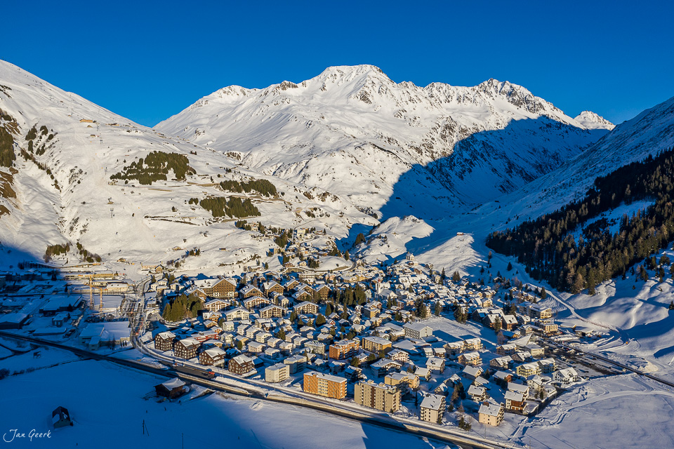 Luftaufnahme von Andermatt im Winter mit schneebedeckten Bergen und Skigebiet Oberalp in der Schweiz – Jan Geerk Fotograf Basel