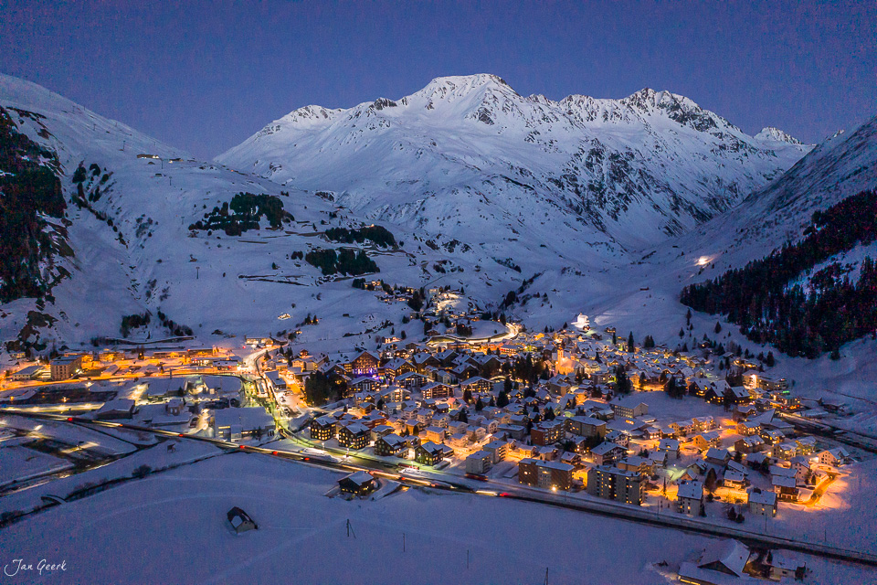Verschneite Berglandschaft mit beleuchteter Ortschaft Andermatt in der Winternacht, Schweiz – Jan Geerk Fotograf Basel