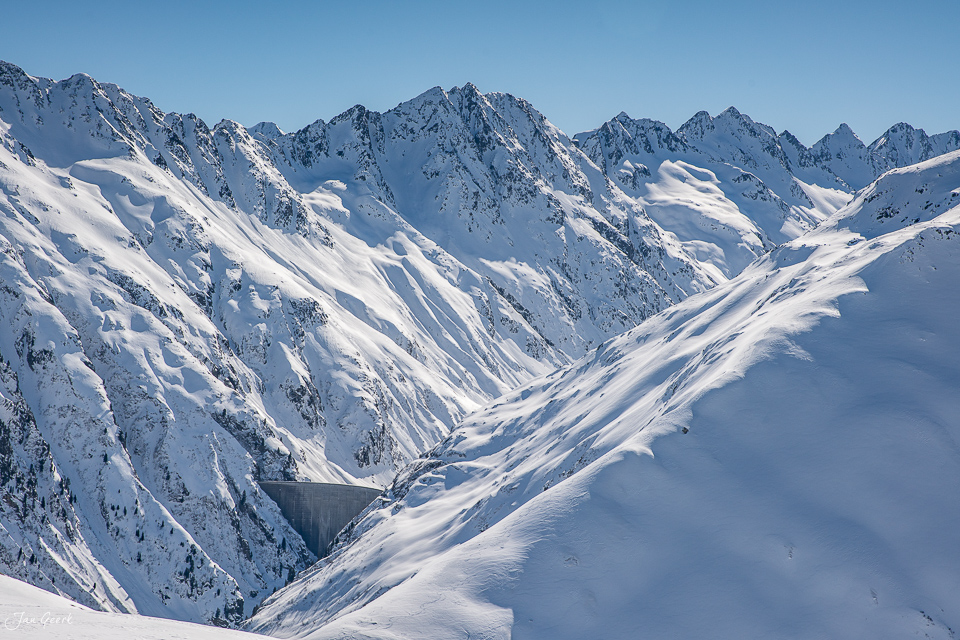 Schneebedeckte Berglandschaft im Skigebiet Oberalp Pass mit verschneiten Gipfeln und Tal im Winter, Schweiz – Jan Geerk Fotograf Basel