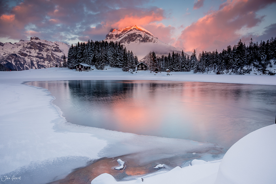 Gefrorener Arnisee im Winter mit schneebedeckten Bergen und rosa Himmel bei Sonnenaufgang in der Zentralschweiz – Jan Geerk Fotograf Basel