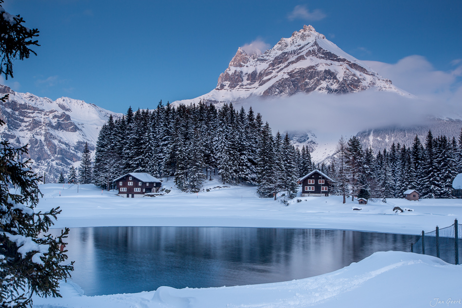 Gefrorener Arnisee mit schneebedeckten Bergen und traditionellen Häusern im Winter in der Zentralschweiz – Jan Geerk Fotograf Basel