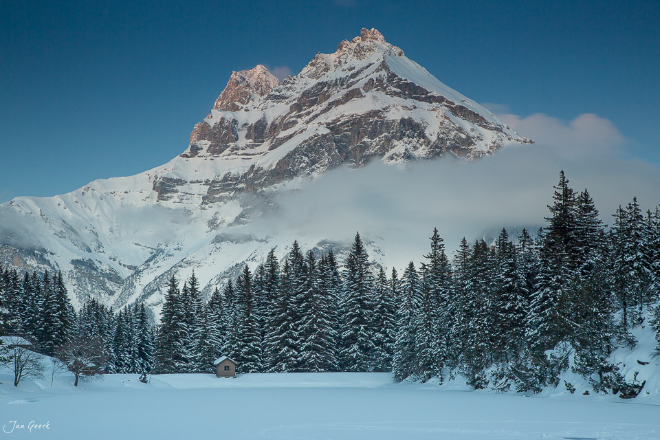 Schneebedeckter Arnisee mit verschneiten Fichten und majestätischem Berg im Hintergrund, Winterstimmung Zentralschweiz Schweiz – Jan Geerk Fotograf Basel