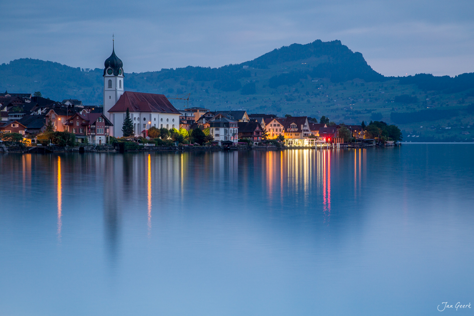 Dorf Beckenried am Vierwaldstättersee mit Kirche spiegelt sich im ruhigen Wasser bei Dämmerung Zentralschweiz Schweiz – Jan Geerk Fotograf Basel