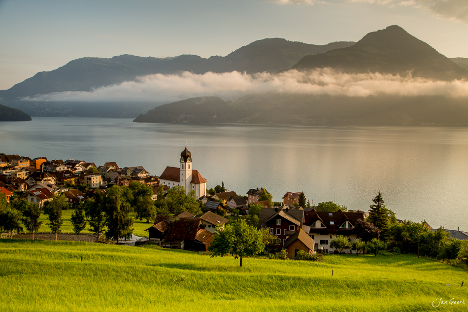 Dorf Beckenried am Vierwaldstättersee mit Kirche, grünen Wiesen und dramatischen Bergen in Sommerstimmung, Zentralschweiz Schweiz – Jan Geerk Fotograf Basel