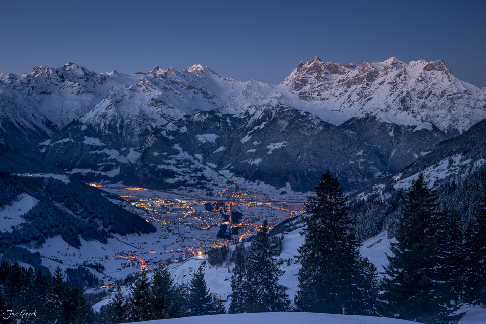 Winterliche Tallandschaft mit schneebedeckten Bergen und leuchtenden Siedlungen in Altdorf in der Zentralschweiz – Jan Geerk Fotograf Basel