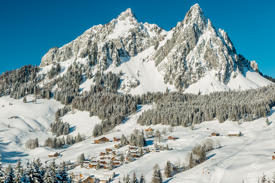 Schneebedeckte Berglandschaft Brunni mit traditionellen Alphütten, verschneiten Mythen-Gipfeln und Fichtenwäldern im Winterlicht, Zentralschweiz – Jan Geerk Fotograf Basel