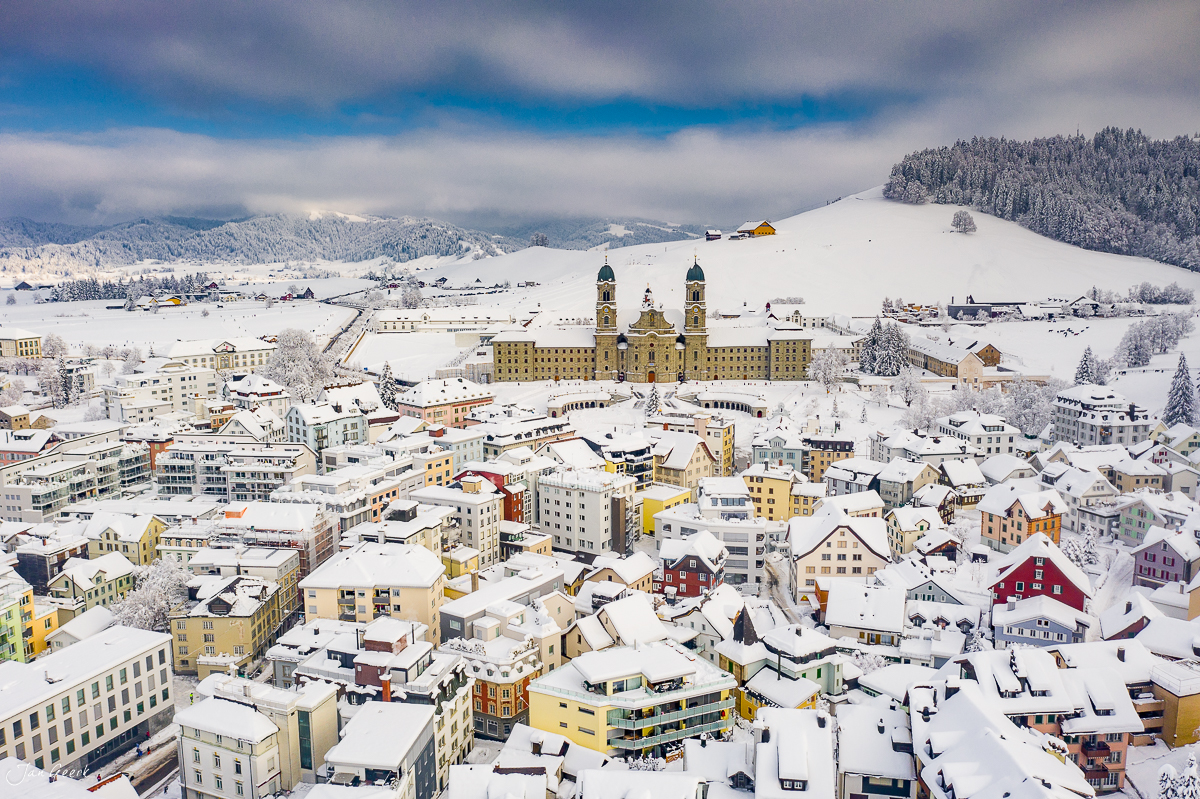 Kloster Einsiedeln im Schnee, Luftaufnahme mit verschneiter Landschaft, Winter in der Schweiz – Jan Geerk Fotograf Basel