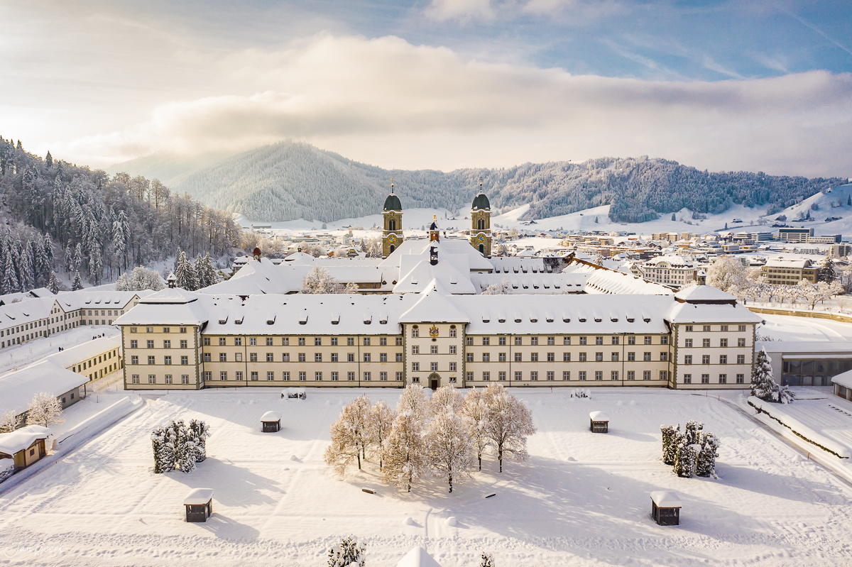 Kloster Einsiedeln Winterlandschaft Luftaufnahme mit schneebedecktem Dach und Bergen Schweiz Jan Geerk Fotograf Basel