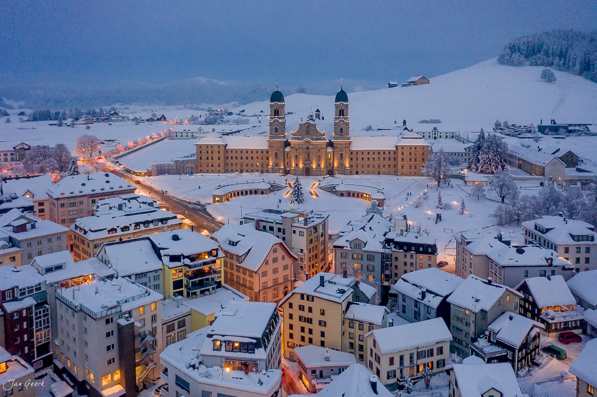 Kloster Einsiedeln mit Schnee bedeckt bei Dämmerung, Luftaufnahme aus der Schweiz – Jan Geerk Fotograf Basel