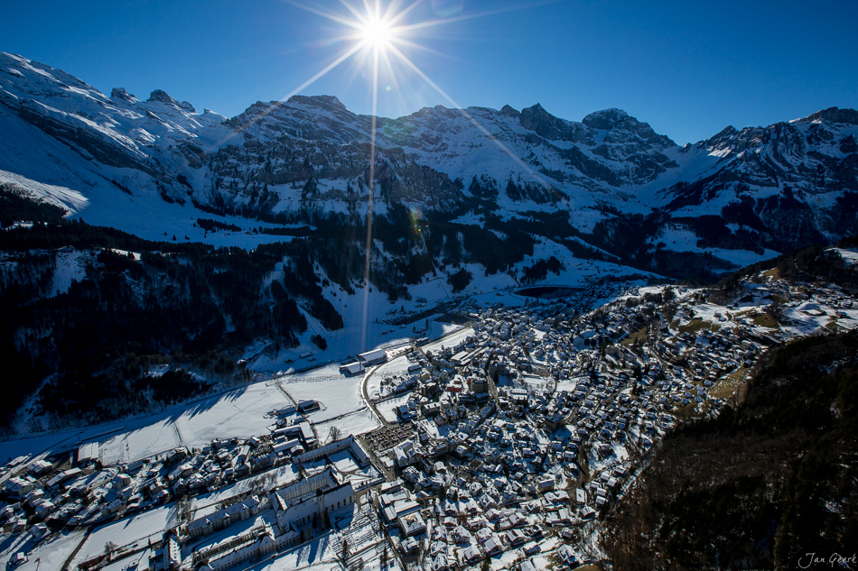 Winterliches Luftbild von Engelberg mit schneebedeckten Bergen, Skigebiet und Gleitschirmflug im Sonnenlicht – Jan Geerk Fotograf Basel