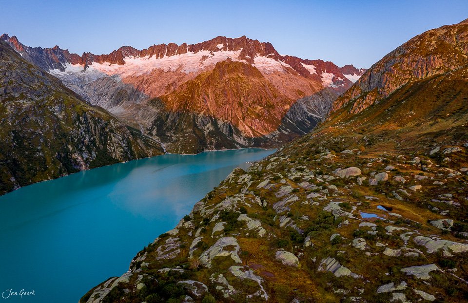 Türkiser Bergsee in der Göscheneralp mit schneebedeckten Gletschern und herbstlichen Felshängen, Uri Schweiz – Jan Geerk Fotograf Basel