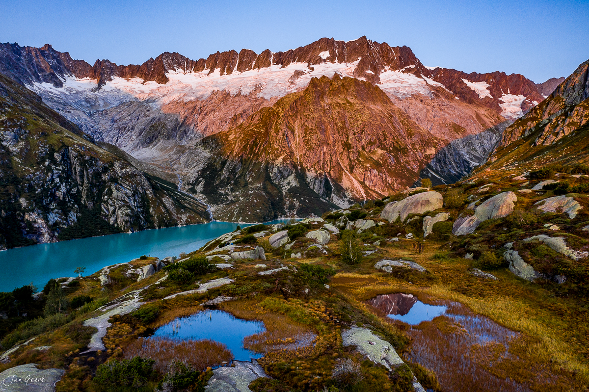 Bergsee Göscheneralp mit türkisblauem Wasser, rotbraunen Felsbergen und Gletschern in der Schweiz – Jan Geerk Fotograf Basel