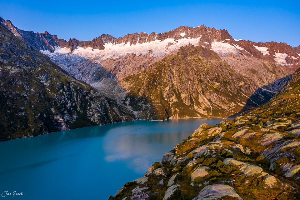 Alpiner Bergsee in der Göscheneralp mit schneebedeckten Gipfeln und Gletschern unter blauem Himmel Schweiz Jan Geerk Fotograf Basel