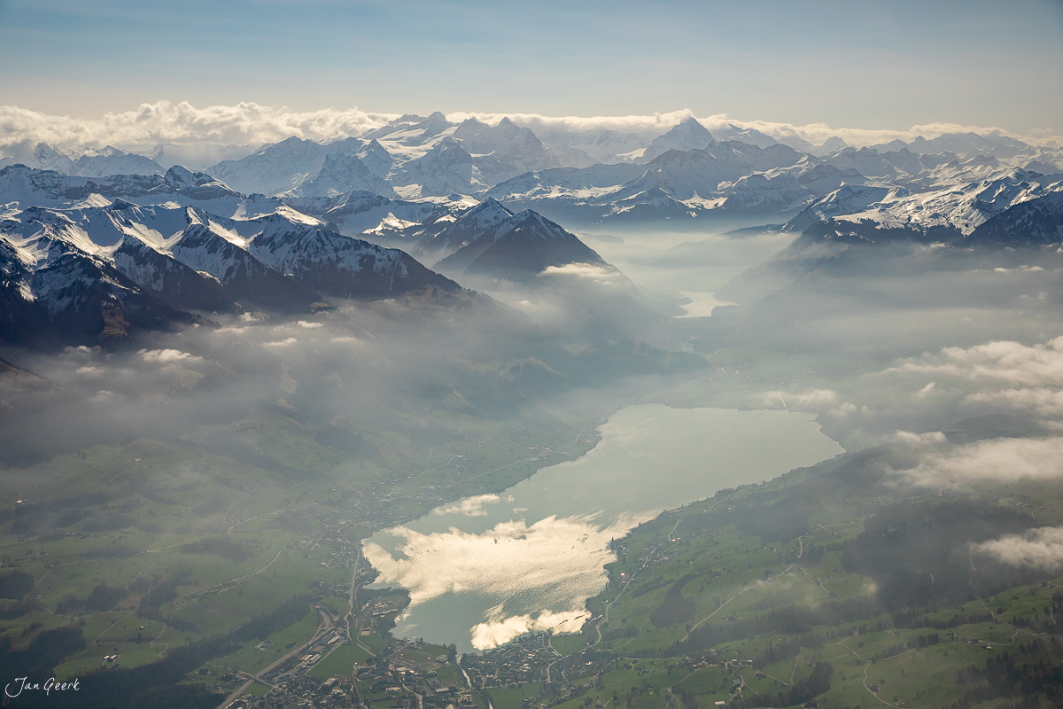 Heliflug über Steingletscher mit verschneiten Alpen, grünem Tal und See im Winter – Zentralschweiz Schweiz – Jan Geerk Fotograf Basel