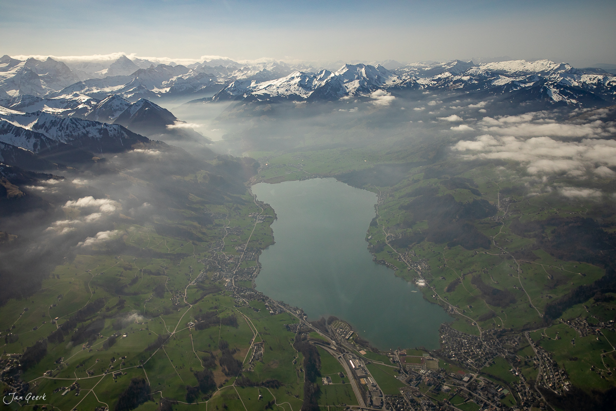 Heliflug über Steingletscher mit schneebedeckten Alpen, türkisem See und grünen Wiesen im Winter – Zentralschweiz, Schweiz – Jan Geerk Fotograf Basel