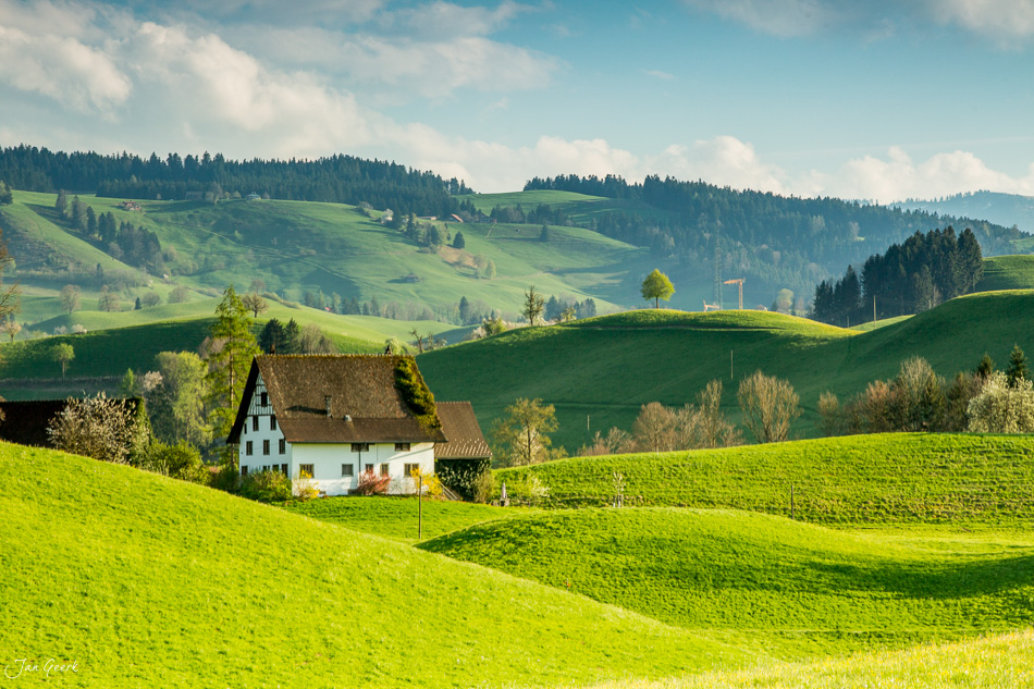Idyllisches Bauernhaus in Hirzel umgeben von grünen Drumlins-Hügeln, Frühjahrslandschaft Zentralschweiz – Jan Geerk Fotograf Basel