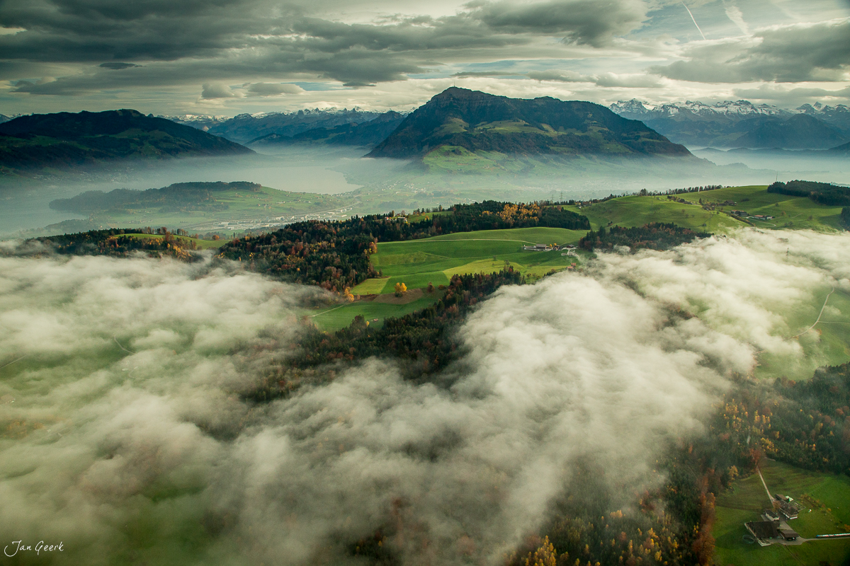Luftaufnahme der Honegg im Herbst mit Nebel, grünen Wiesen und Alpenpanorama, Zentralschweiz – Jan Geerk Fotograf Basel