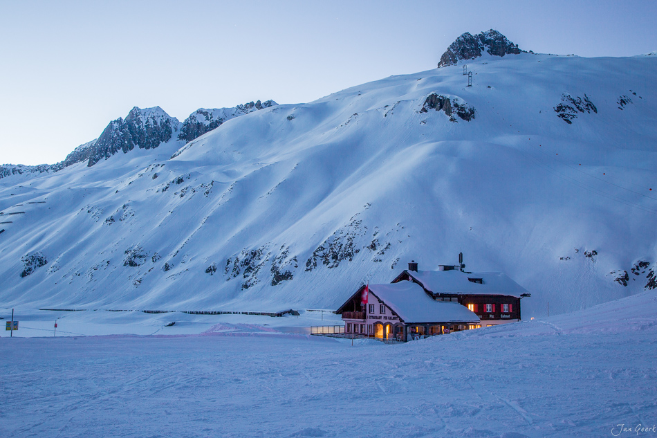 Beleuchtetes Berghotel in verschneiter Winterlandschaft am Oberalppass mit schneebedeckten Bergen Schweiz – Jan Geerk Fotograf Basel