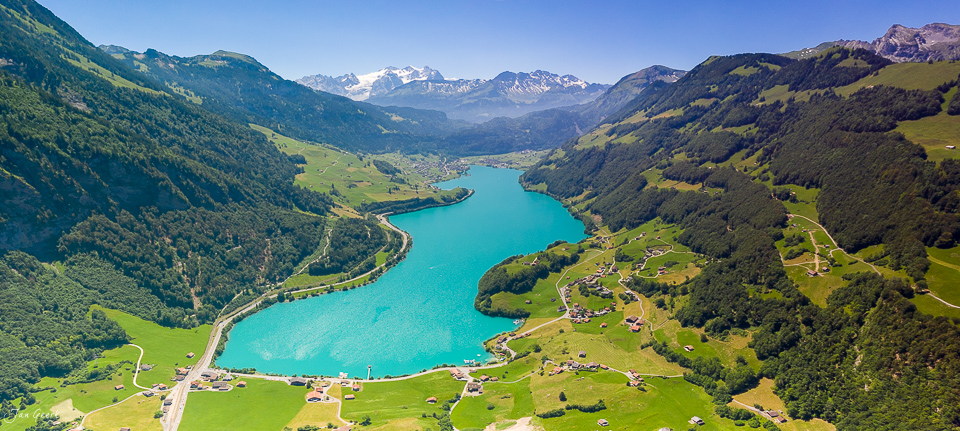 Türkisblauer Bergsee mit grünen Alpenwiesen, umgeben von bewaldeten Bergen im Sommer, Zentralschweiz – Jan Geerk Fotograf Basel