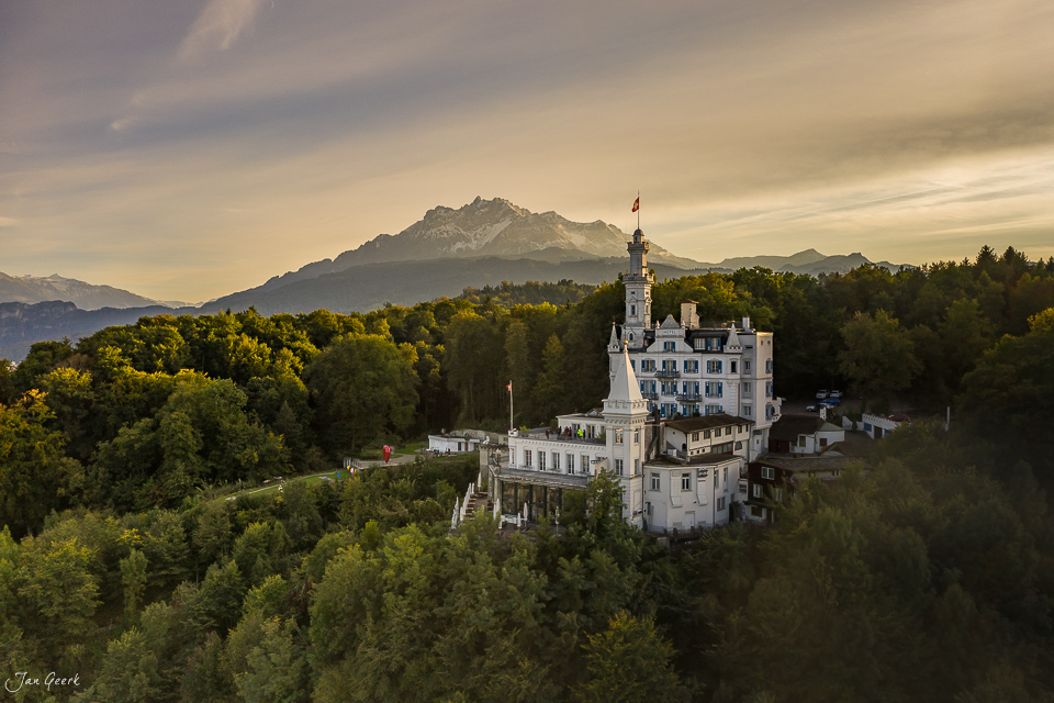 Schloss Neuschwanstein-ähnliches Märchenschloss in Waldlandschaft mit schneebedecktem Berg im Hintergrund, Sommerlicht, Zentralschweiz Schweiz – Jan Geerk Fotograf Basel
