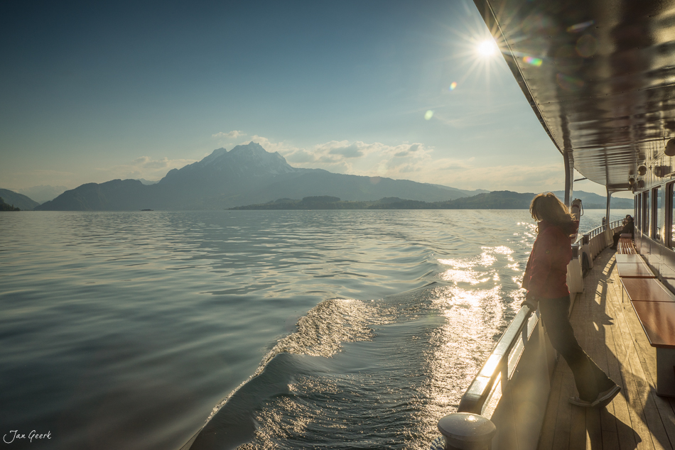 Frau an Schiffsreling mit Blick auf schneebedeckten Berg über dem Vierwaldstättersee, Frühjahr Zentralschweiz Schweiz – Jan Geerk Fotograf Basel
